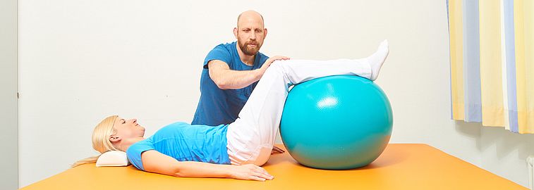 Mann leitet Frau zu Übungen mit Gymnastikball an